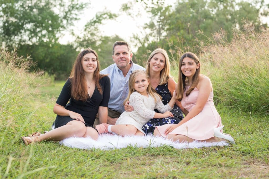 Family sitting together on grass outdoors.
